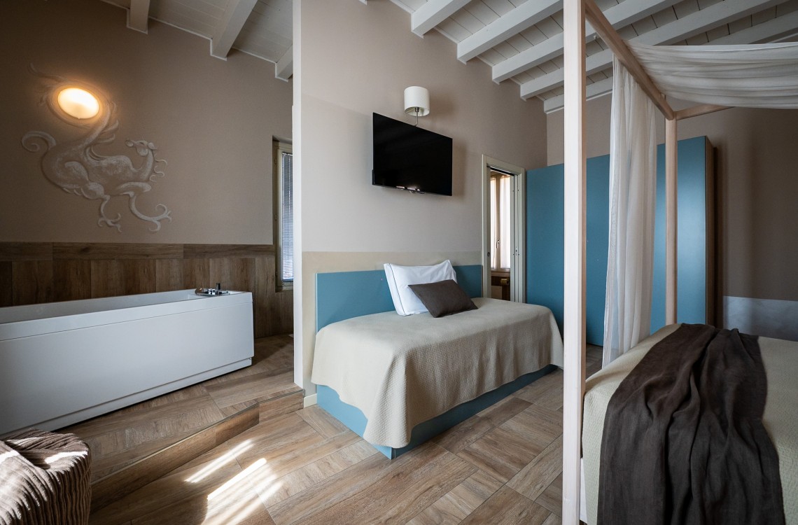 Disposta a godere della suggestiva vista dello specchio d'acqua, che avvolge in un abbraccio l'antico complesso rurale, in un ambiente arredato con stile caldo ed elegante, è stata progettata per farvi rilassare in un'atmosfera magica dotata di ogni confort. La suite, di complessivi 42mq, è resa unica dalla presenza di un accogliente letto a baldacchino e di una vasca, con vista sulla camera e sul fontanile, dotata di idromassaggio e cromoterapia. Il divano può essere trasformato in un comodo terzo letto. <br>Disponibile uso SINGOLA, uso DOPPIA e uso TRIPLA.<br>